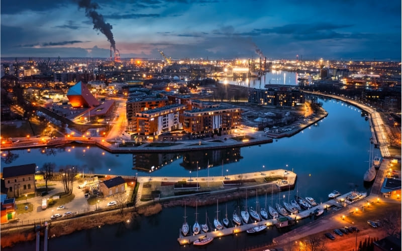 Nocna panorama Gdańska z widokiem na Motławę, marinę, oświetlone nabrzeża i tereny portowe miasta
